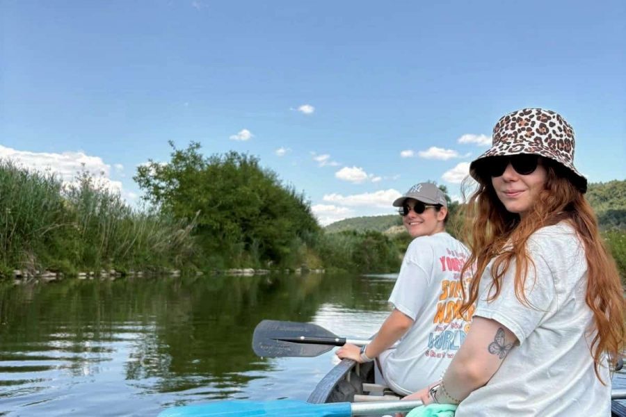 Zwei Mitarbeiterinnen paddeln auf dem Fluss bei Sonnenschein.