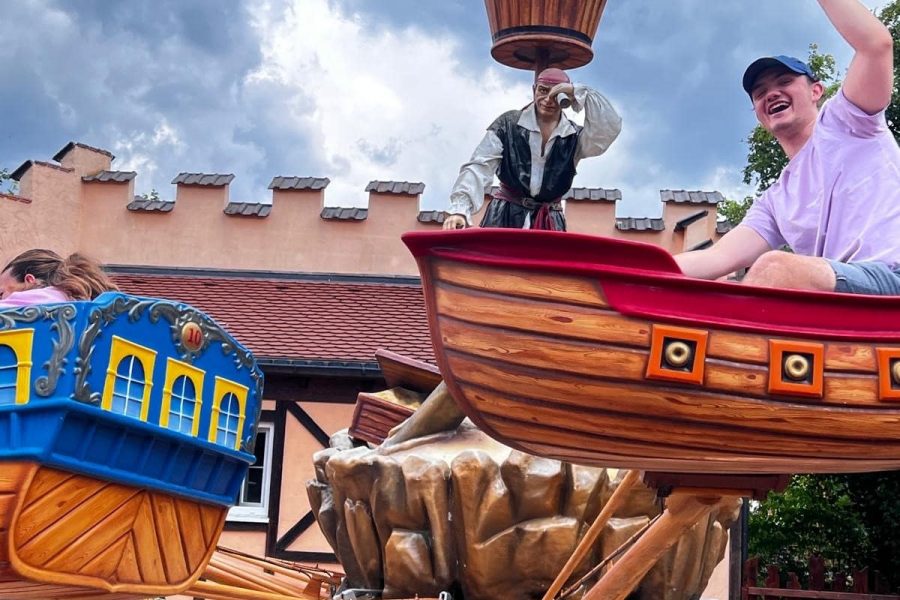 Mitarbeiter jubelt im Piratenschiff-Karussell im Freizeitpark.