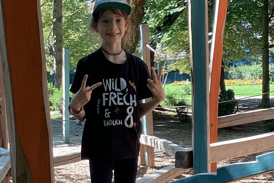 Lachendes Kind mit Cap auf einem Spielplatz im Park.