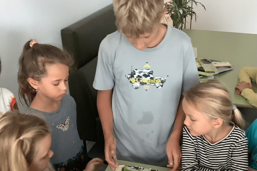 Kinder bereiten gemeinsam Sushi auf einer Bambusmatte zu.