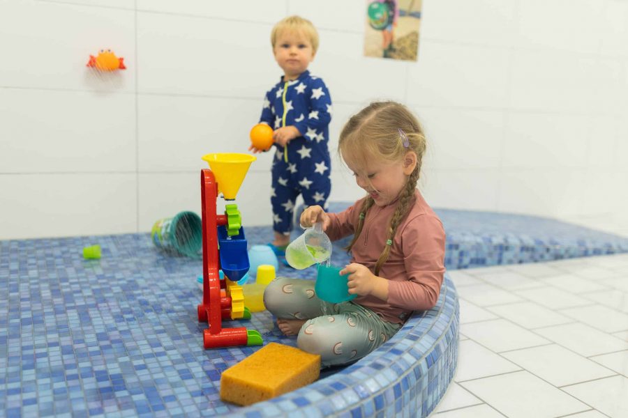 Kinder beim Wasserspiel im Nassraum.