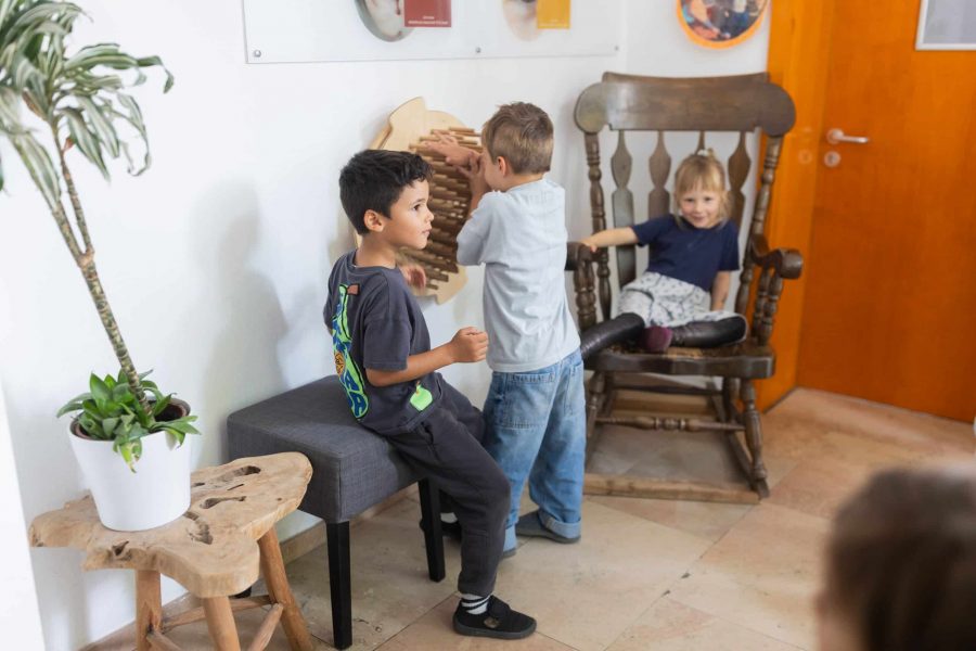 Drei Kinder im Gruppenraum, zwei spielen an einem Holz-Wandelement.