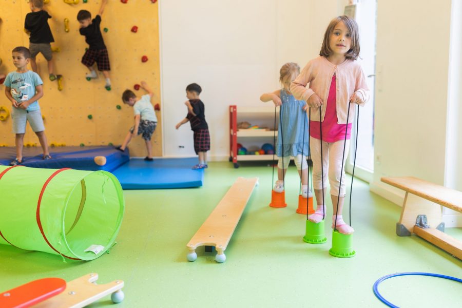 Kinder balancieren im Bewegungsraum der bürgerhilfe ingolstadt KiTa GmbH auf Stelzen und entdecken spielerisch ihre motorischen Fähigkeiten