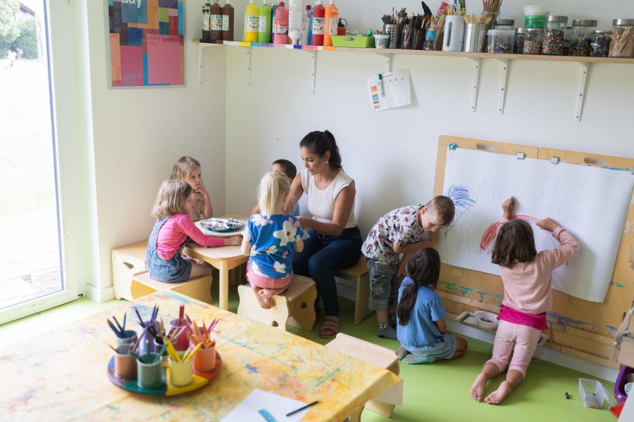 Kinder malen und basteln gemeinsam mit einer pädagogischen Fachkraft im Kreativraum der bürgerhilfe ingolstadt KiTa GmbH