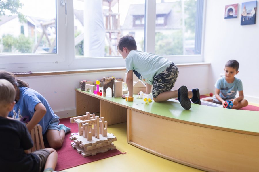 Kinder bauen mit Holzbausteinen und Spielmaterialien im Gruppenraum einer Kindertagesstätte der bürgerhilfe ingolstadt KiTa GmbH
