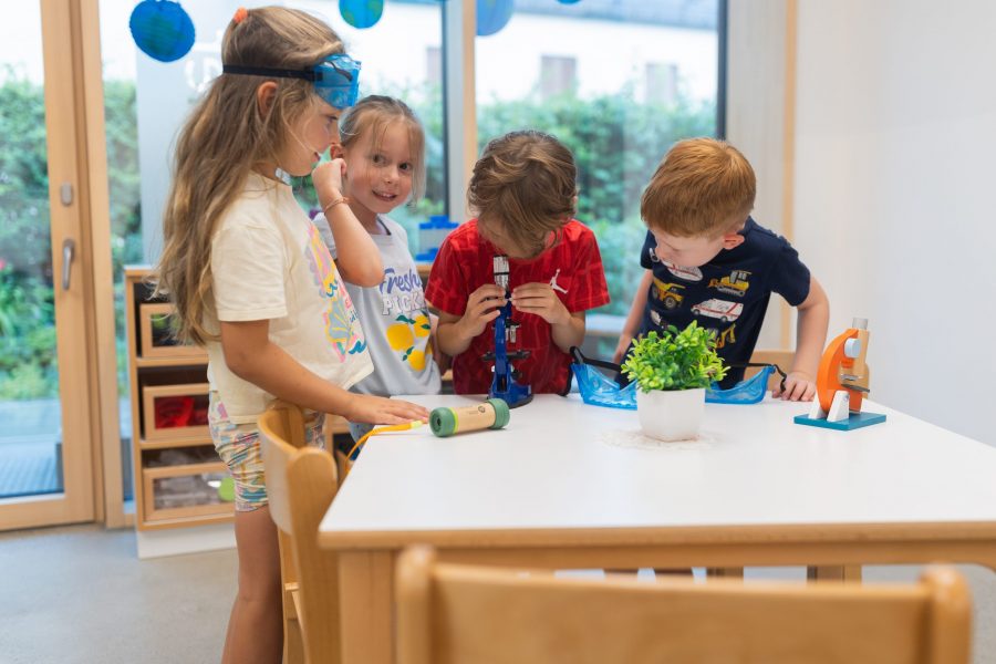 Kinder erforschen gemeinsam Pflanzen mit Lupen und einem Mikroskop in einer Kindertagesstätte in Ingolstadt.