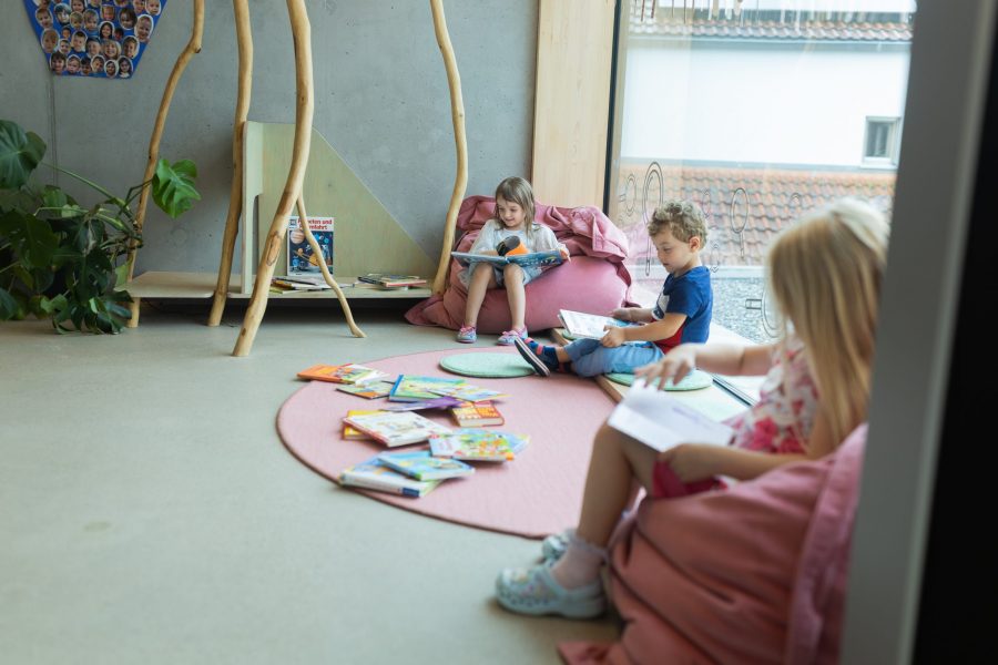 Kinder lesen und betrachten Bücher in einer gemütlichen Leseecke einer Kindertagesstätte in Ingolstadt.