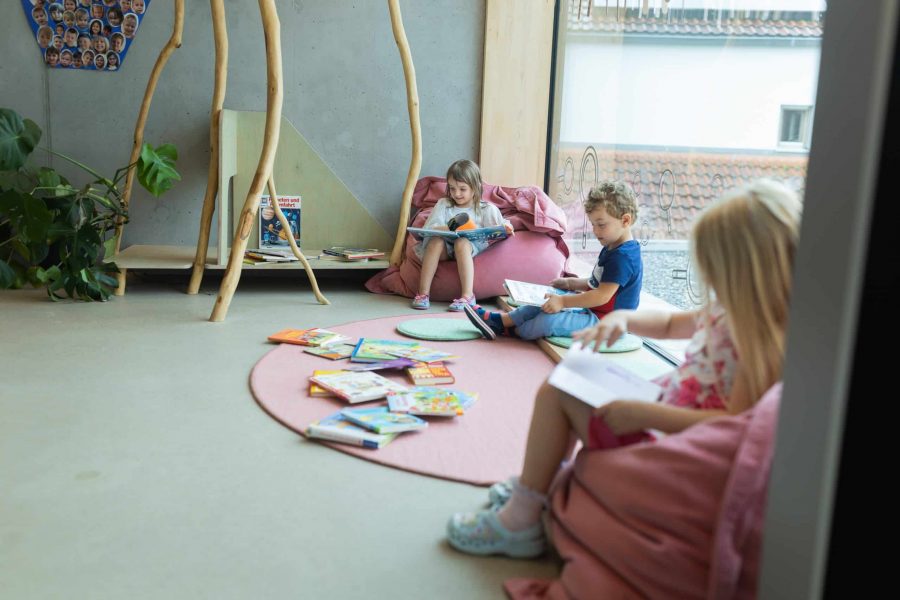 Kinder lesen Bücher in der gemütlichen Leseecke der Kita.