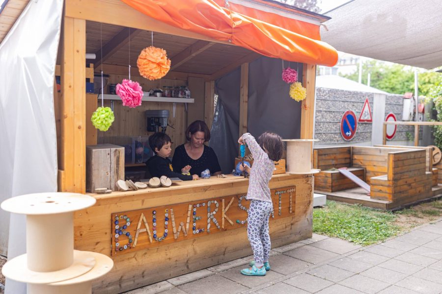 Kinder spielen am Bauwagen-Kiosk im Garten der Kita.