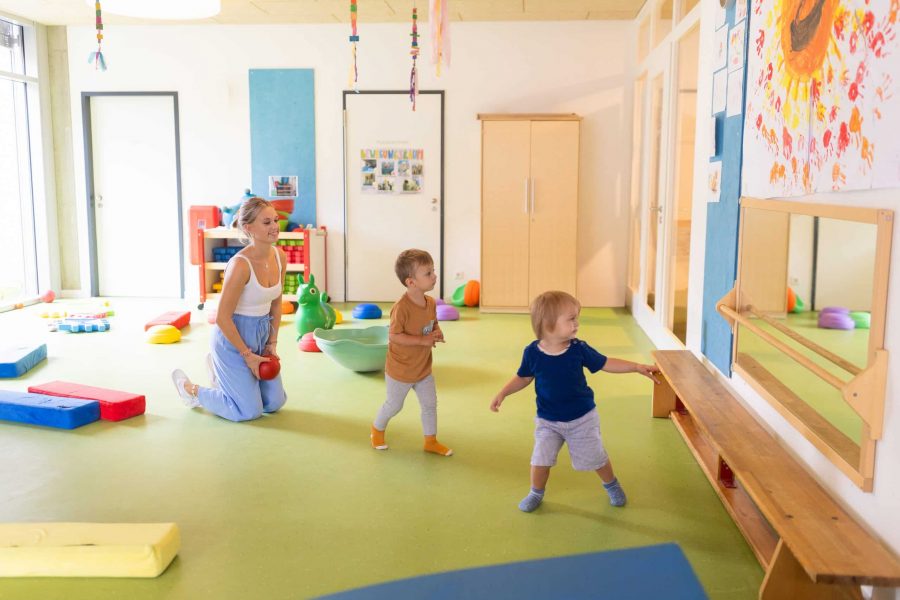 Kleinkinder mit Erzieherin im Bewegungsraum.