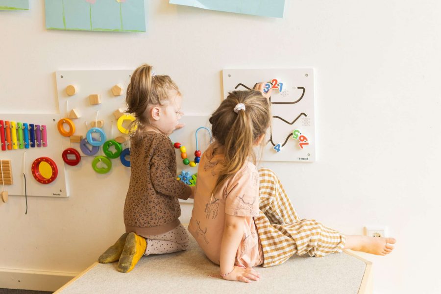 Zwei Kinder spielen konzentriert an einer Motorik- und Zahlenwand.