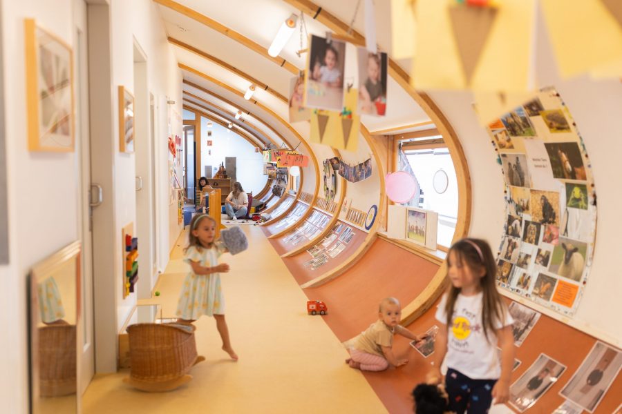 Kinder spielen und bewegen sich frei in einem hellen, kindgerecht gestalteten Flur einer Kindertagesstätte in Ingolstadt.