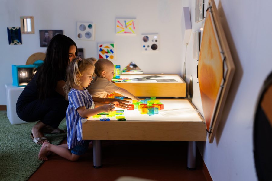 Kinder unterschiedlichen Alters experimentieren an einem Leuchttisch mit Farben und Formen in einer Kindertagesstätte in Ingolstadt.