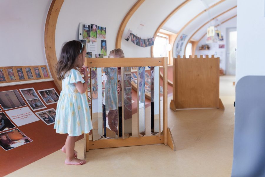Ein Kind betrachtet sein Spiegelbild in einem kindgerechten Spielelement im Flur einer Kindertagesstätte in Ingolstadt.