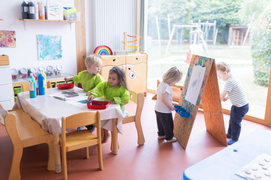 Kinder malen und gestalten gemeinsam im Atelier einer Kindertagesstätte in Ingolstadt mit Farben und Pinseln.