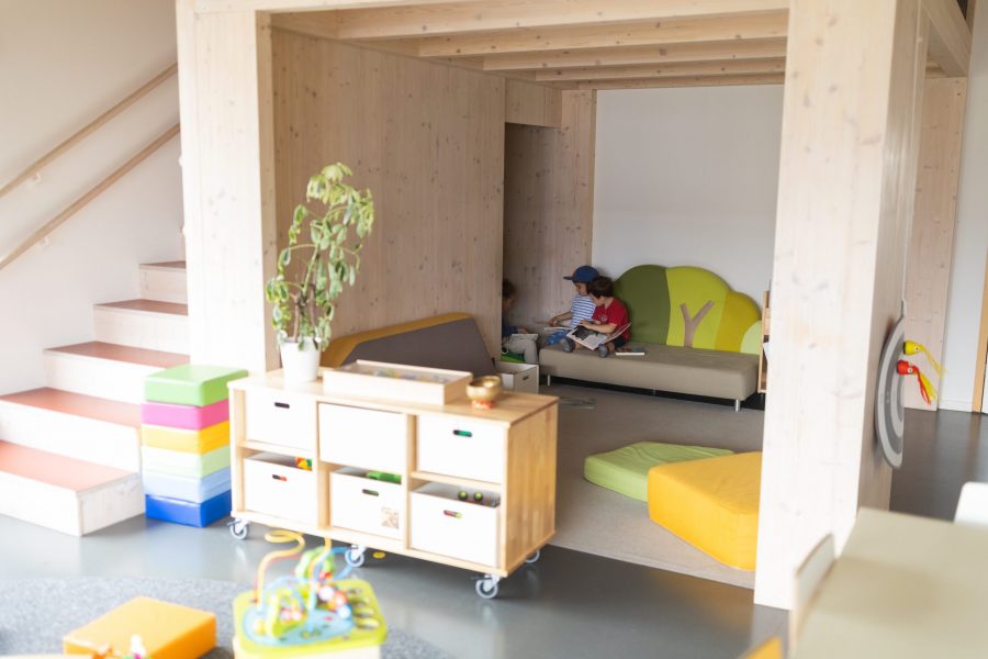 Kinder sitzen gemeinsam in einer gemütlichen Leseecke und schauen Bücher im KinderGlück an.