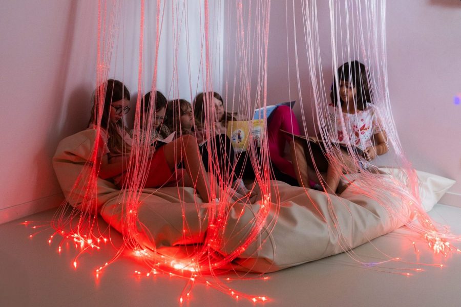 Kinder sitzen entspannt in einem Snoezelraum mit Lichtfasern und lesen gemeinsam in einer Kindertagesstätte in Ingolstadt.