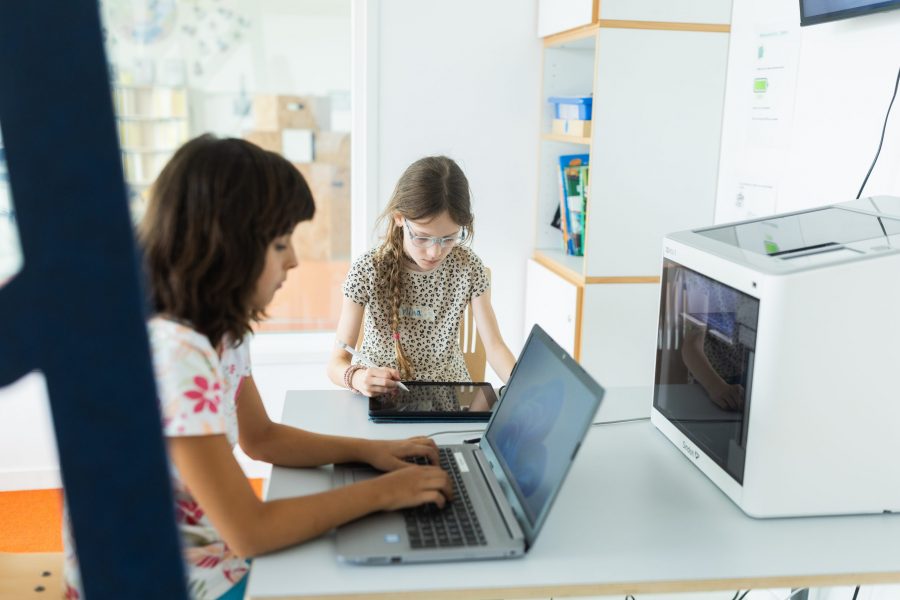 Kinder arbeiten mit Tablet und Laptop an einem Tisch in einer Kindertagesstätte in Ingolstadt.