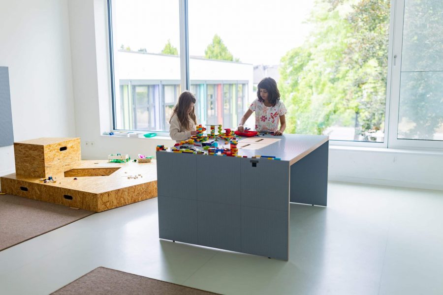 Zwei Kinder bauen mit Bausteinen am Tisch.