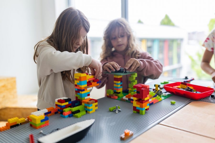 Zwei Kinder bauen gemeinsam mit bunten Bausteinen an einem Tisch in einer Kindertagesstätte in Ingolstadt.